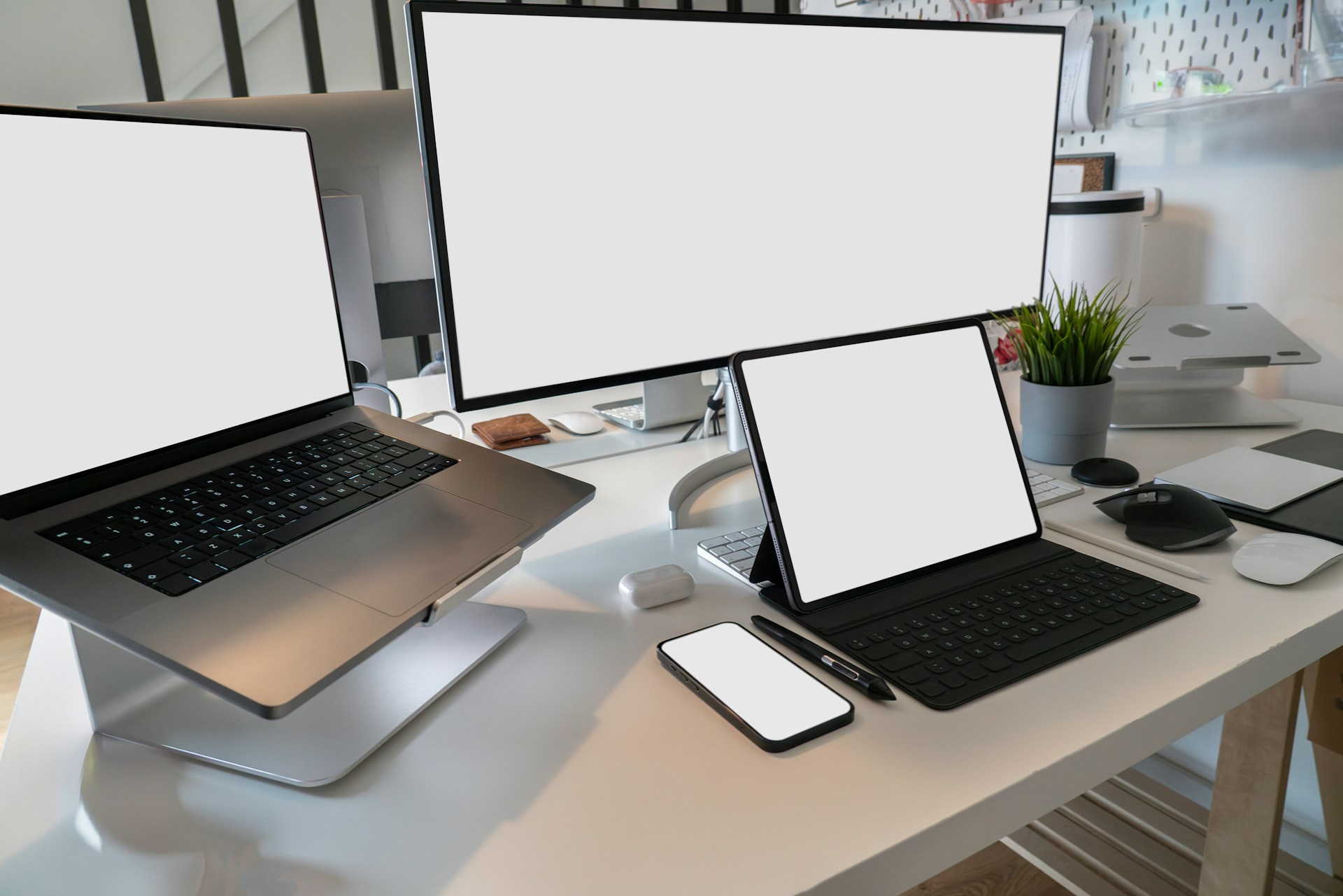 sebuah meja dengan sebuah laptop, sebuah ponsel, sebuah tablet dan sebuah layar monitor